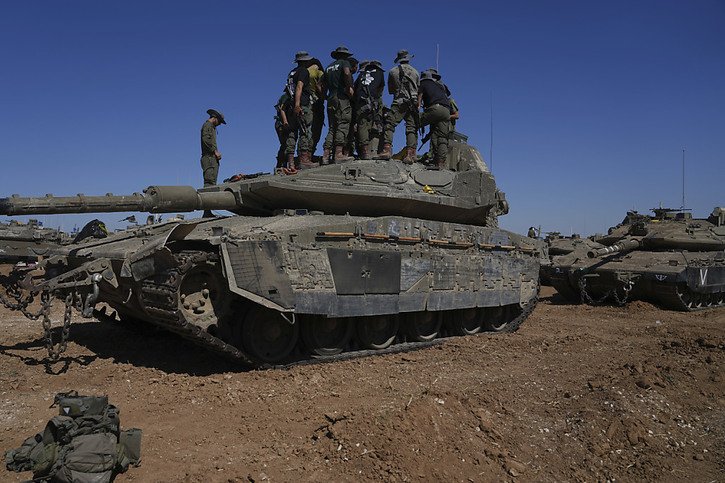 Des soldats israéliens se tiennent sur un véhicule militaire blindé sur une aire de repos près de la frontière entre Israël et Gaza. © Keystone/AP/Tsafrir Abayov