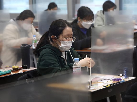 Des cloisons transparentes ont été installées sur chaque bureau et le port du masque est obligatoire durant toute l'épreuve de l'examen annuel d'entrée à l'université en Corée du Sud. © KEYSTONE/EPA/CHUNG SUNG-JUN / POOL
